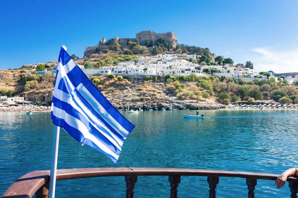 A Greek flag flying in front of ancient ruins